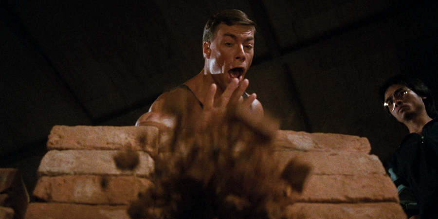 Jean-Claude Van Damme uses his IT prowess to explode a specific brick, which he is certain won't hit back (image property of Warner Bros.)