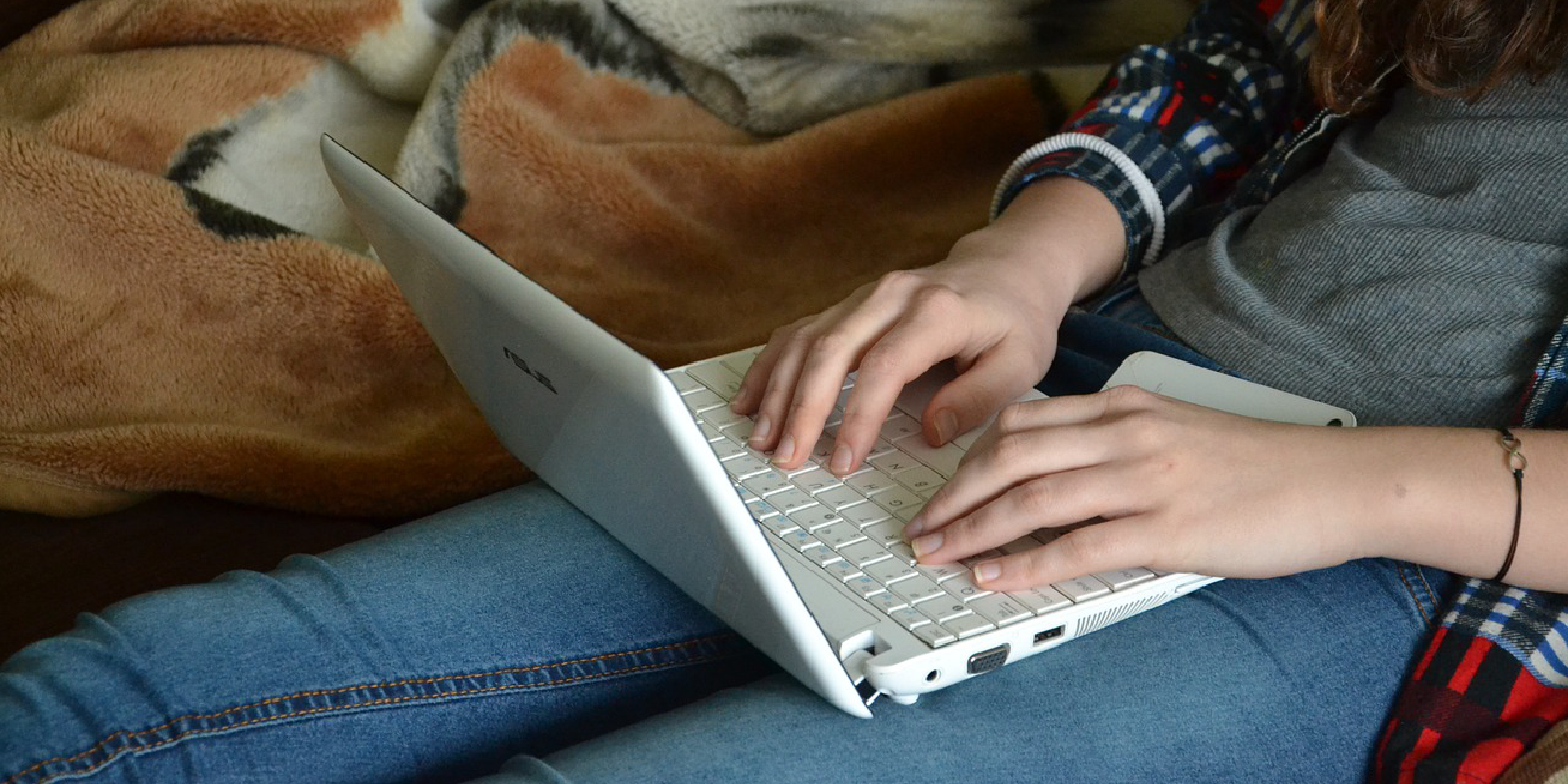 Photo of a person sitting with legs outstretched, using a laptop